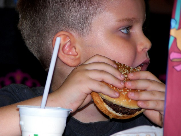 Criança comendo hamburguer