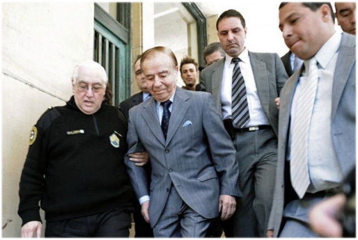 O ex-presidente argentino Carlos Menem cercado de guardas na saída do tribunal