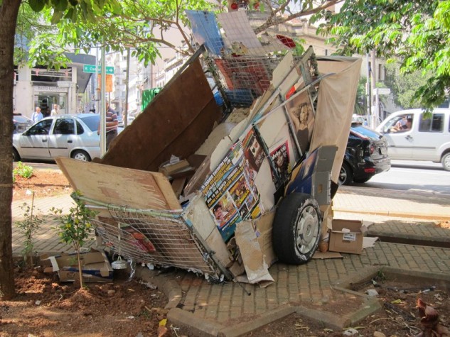 A obra de arte é uma carroça coberta de papelão, lixo e recortes de revista