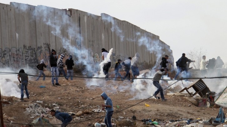 Manifestantes palestinos procuram local seguro contra bomba de gás lacrimogêneo